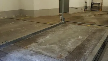 Geräumige Garage mit Betonboden und einer Hebebühne oder Inspektionsgrube, ideal für Fahrzeuge.