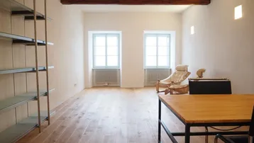 Helles, geräumiges Zimmer mit Holzbalken, Parkettboden und zwei Fenstern, ideal als Wohn- oder Arbeitsbereich.