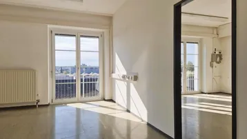 Heller Büroraum mit großen Fenstern, die viel Tageslicht hereinlassen und einen weiten Blick bieten.