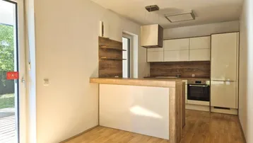 Helle Küche mit Holzboden, moderner Einbauküche und integrierter Frühstücksbar.