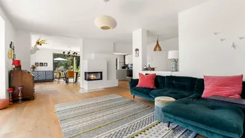 Gemütlicher Wohnbereich mit Kamin, bequemer Couch und Blick in den offenen Essbereich.