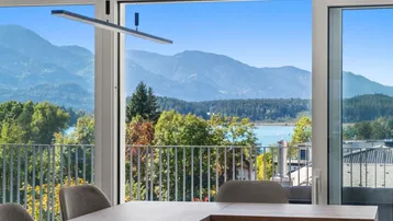 Heller Wohnbereich mit Esstisch und beeindruckendem Blick auf den See und die Berge.