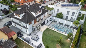 Luftaufnahme des Anwesens mit großem Garten, Pool und Terrasse, umgeben von Wohnbebauung.