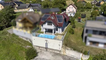 Luftaufnahme eines Hauses mit Pool und Solaranlage auf dem Dach in ländlicher Umgebung.