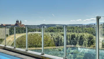 Panoramablick vom Poolbereich mit Glasgeländer auf die Donau und das Stift Melk.