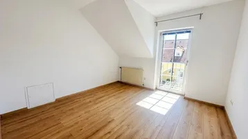 Helles Schlafzimmer im Dachgeschoss mit Laminatboden und französischem Balkon.