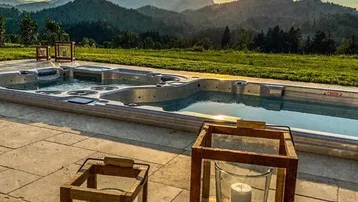 Abendstimmung auf der Terrasse mit Whirlpool, Bergblick und dekorativen Laternen bei Sonnenuntergang.