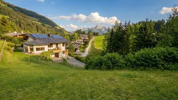 Idyllisches Anwesen in den Bergen mit Photovoltaikanlage und weitem Blick auf die grüne Landschaft.