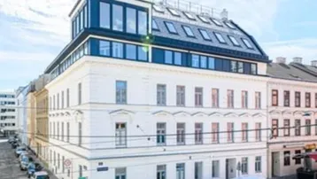 Modernisiertes Mehrfamilienhaus mit Dachgeschossausbau und klassischer Fassade an einer Stadtstraße.
