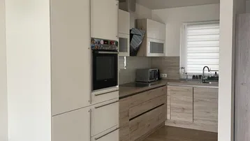 Moderne Einbauküche mit weißen und holzfarbenen Schränken sowie integriertem Backofen.
