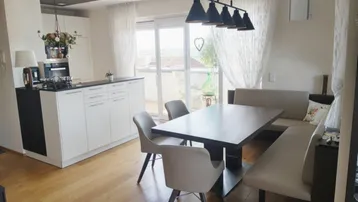 Moderne offene Küche mit weißen Schränken, Esstisch und Zugang zur Terrasse.