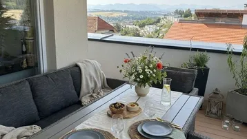 Gemütlicher Balkon mit Esstisch, Sitzgelegenheiten und weitem Blick über die Landschaft.