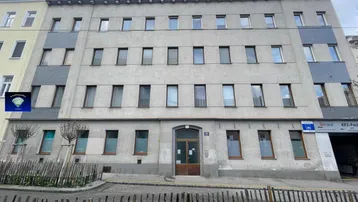 Die Fassade des Gebäudes zeigt eine schlichte Architektur mit mehreren Reihen von Fenstern und einem Eingangsbereich.