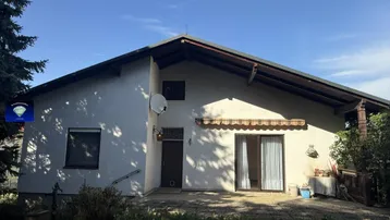 Einfamilienhaus mit heller Fassade, Satteldach und Zugang zum Gartenbereich.