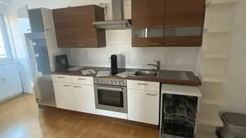 Moderne Küche mit Holz- und weißen Schränken, Einbauherd, Spüle und einem Geschirrspüler.