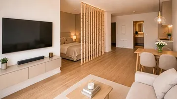 Modernes offenes Wohnkonzept mit Schlafbereich, Essplatz und Wohnzimmer, getrennt durch eine Holzlamellenwand.