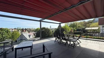 Geräumige Dachterrasse mit Sitzgelegenheiten, Markise und weitem Blick über die Stadt.