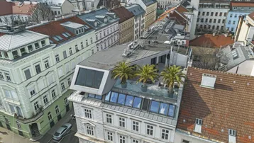 Luftaufnahme eines modernen Dachausbaus auf einem historischen Gebäude in städtischer Umgebung.