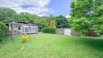 Großer Garten mit Rasenfläche, altem Baumbestand und überdachter Terrasse am Haus.