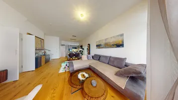 Geräumiges Wohnzimmer mit großem Ecksofa, Holzboden und offener Verbindung zur Küche.
