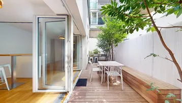 Heller Wohnbereich mit Holzboden, Bartresen und großen Glasfalttüren, die zu einer Holzterrasse führen.