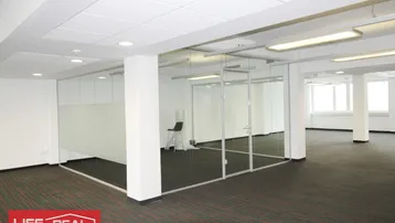 Geräumiges Büro mit Teppichboden, weißen Wänden und modernen Glasabtrennungen für separate Arbeitsbereiche.