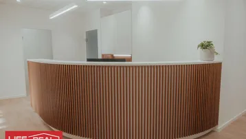 Moderner Empfangsbereich mit Holzlamellen-Theke und heller Beleuchtung in einem Büro oder einer Praxis.