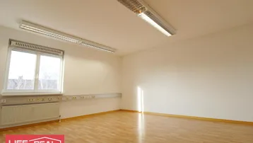 Heller Raum mit Holzfußboden, großem Fenster und Deckenbeleuchtung, ideal als Büro oder Arbeitszimmer.