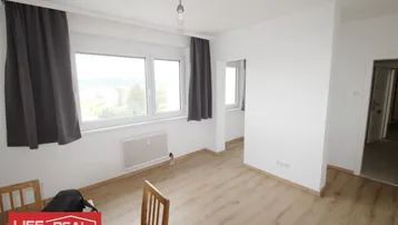 Helles Zimmer mit Laminatboden, großen Fenstern und Blick ins Grüne.