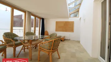 Heller Wintergarten mit großen Fenstern, Oberlicht und Rattanmöbeln, ideal für entspannte Mahlzeiten.
