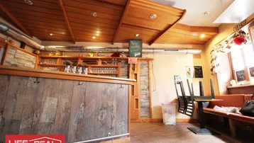 Rustikaler Barbereich mit Holzbalkendecke, einer Theke aus Altholz und gemütlichen Sitzgelegenheiten.