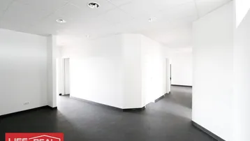 Heller Büroraum mit weißen Wänden und dunklem Fliesenboden, ausgestattet mit Einbaustrahlern in der Decke.