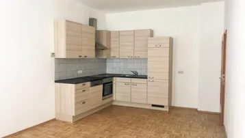 Funktionale Küche mit hellen Holzschränken, dunkler Arbeitsplatte und integrierten Geräten.