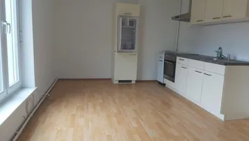 Helle Wohnküche mit Laminatboden, Einbauküche und Kühlschrank, bietet Platz für einen Essbereich.