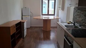 Länglicher Raum mit kleiner Küchenzeile, Esstisch, Kühlschrank und Fenster, ausgestattet mit Laminatboden.
