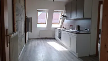 Helle Dachgeschossküche mit modernen weißen Schränken, Holzdetails und zwei Dachfenstern.
