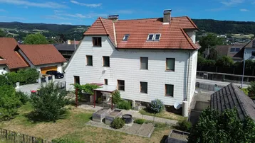 Luftaufnahme des Hauses mit rotem Ziegeldach, weißer Fassade und einem kleinen Gartenbereich.