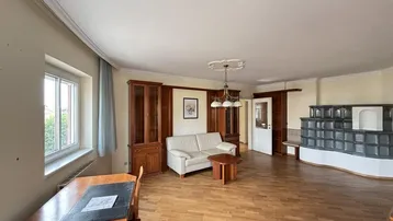 Geräumiges Wohnzimmer mit Parkettboden, Kachelofen und klassischer Einrichtung.