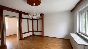 Helles Wohnzimmer mit Parkettboden, Holzelementen und einem dekorativen Kronleuchter an der Decke.