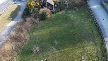 Luftaufnahme eines unbebauten Grundstücks mit Rasenfläche, umgeben von Straßen und Häusern.