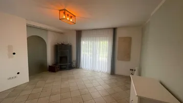 Helles Wohnzimmer mit Fliesenboden und einem modernen Kaminofen für gemütliche Abende.