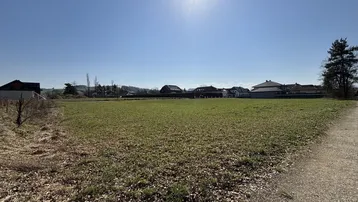 Sonniges Grundstück mit weitem Blick auf die umliegende Landschaft und Wohnbebauung im Hintergrund.