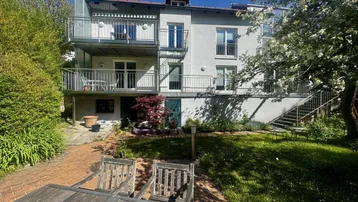 Gebäudeansicht mit mehreren Balkonen und einem gepflegten Gartenbereich im Vordergrund.