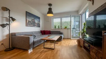 Helles Wohnzimmer mit großem Ecksofa, Holzboden und Zugang zur Terrasse.