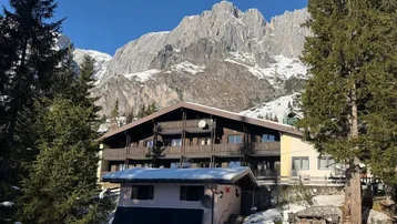 Traditionelles Gebäude in den Bergen mit Holzbalkonen und schneebedeckter Landschaft.