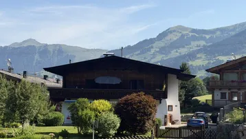 Traditionelles Haus im alpinen Stil mit Holzbalkonen und Bergblick in sonniger Lage.