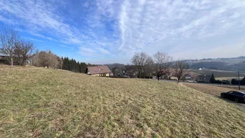 Weitläufiges Grundstück mit sanfter Hanglage und Blick auf die umliegende Landschaft und Häuser.