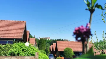 Blick auf die umliegende Siedlung mit roten Dächern und grüner Landschaft unter blauem Himmel.