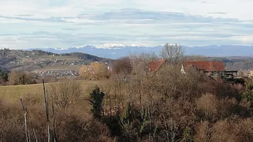 Panoramablick über die hügelige Landschaft mit fernen schneebedeckten Bergen am Horizont.