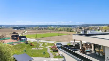 Weitläufige Dachterrasse mit Essbereich und Lounge-Möbeln, umgeben von grüner Landschaft.